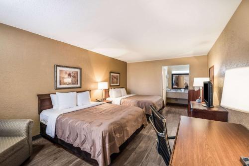 阿卡德尔菲亚Quality Inn Arkadelphia - University Area的酒店客房设有两张床和一张桌子。