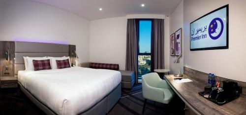 迪拜Premier Inn Dubai Barsha Heights的配有一张床和一张书桌的酒店客房