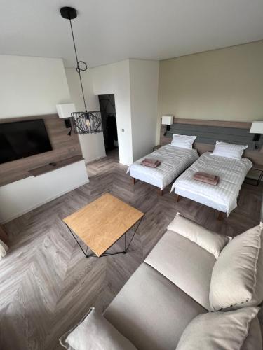 Naujoji AkmenėMOYA Apartmentai的一间带三张床和一张沙发的客厅