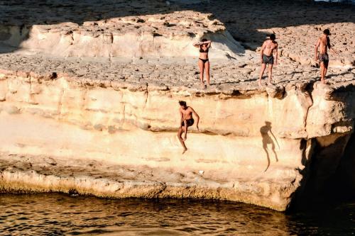 斯利马外交官酒店的一群人从悬崖跳进水中