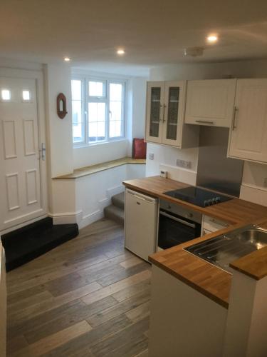 甘尼斯莱克Crossways Corner Cottage的厨房铺有木地板,配有白色橱柜。