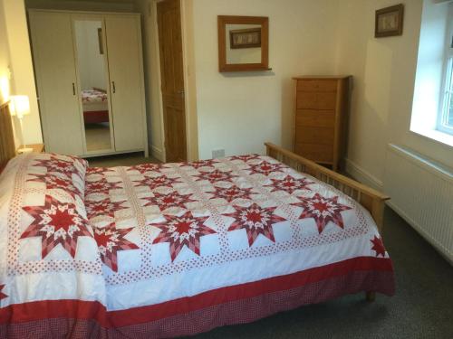 甘尼斯莱克Crossways Corner Cottage的一间卧室配有一张带红白毯子的床