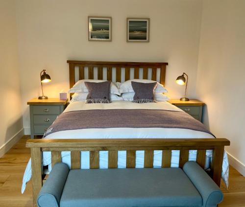 巴拉胡利什The Heronry Hideaway with luxury hot tub的一间卧室配有一张大床和蓝色长凳