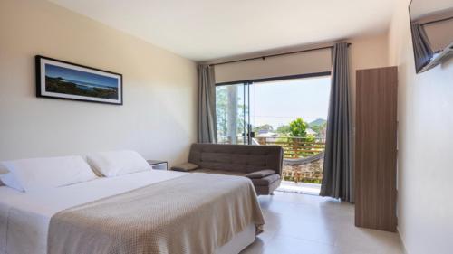 普腊亚罗萨Recanto Sol&Mar的一间卧室配有一张床、一张沙发和一个窗口