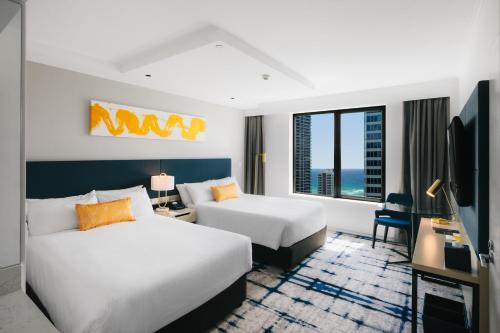黄金海岸voco Gold Coast, an IHG Hotel的酒店客房配有两张床和一张书桌