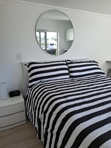 陶朗加Pod bach on Tweed的卧室配有黑白条纹床和镜子