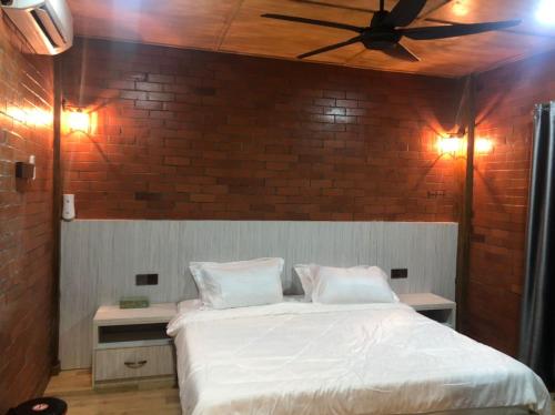 KerlingKemuning Orchard Villaa的卧室配有白色的床和砖墙