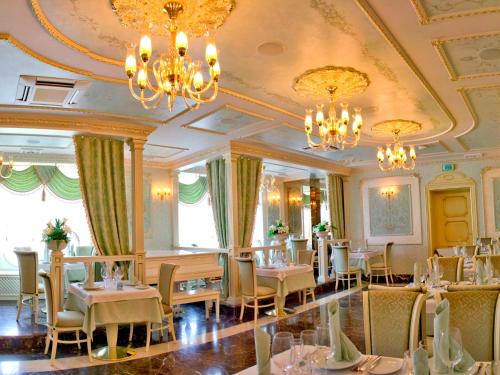 波尔塔瓦阿里亚格兰德酒店的餐厅设有桌椅和吊灯。