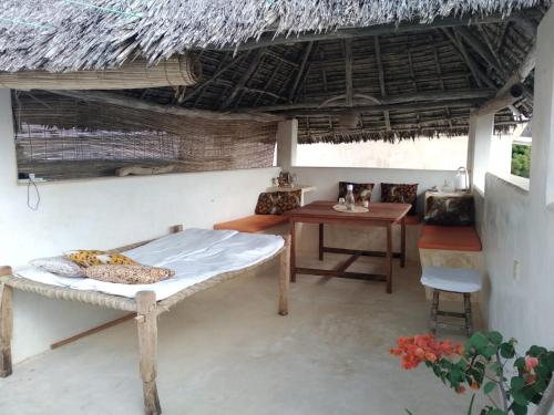 ShelaFuraha House的一间卧室设有一张床铺、一张桌子和稻草屋顶。
