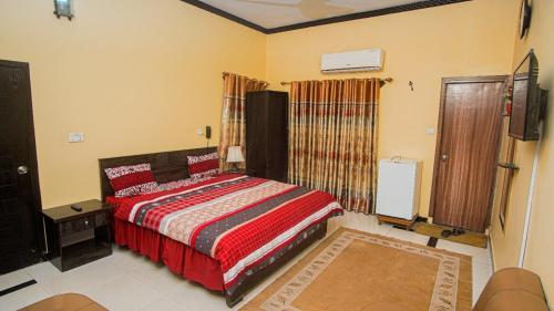 卡拉奇Seasons Inn的一间卧室配有一张红色棉被的床