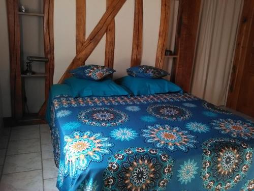 DoschesChambre d'Hôtes des P'tits Bonheurs的一张带蓝色棉被和枕头的床