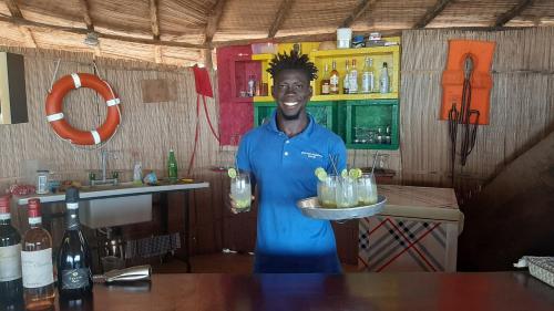 BruceAfrican Ecolodge Angurman的站在酒吧里拿着饮料盘的人
