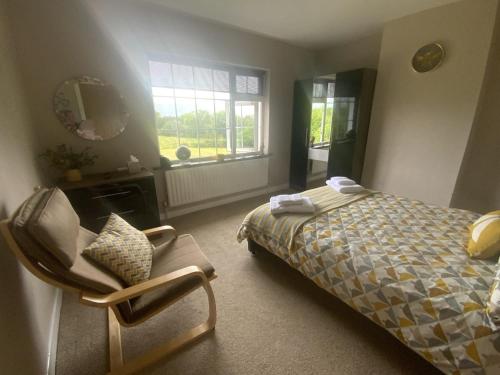GreenaneBroomfields的卧室配有床、椅子和窗户。