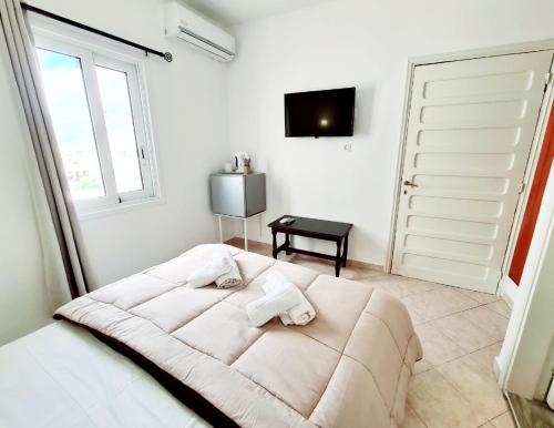 卡尔帕索斯Avra Rooms的白色的卧室设有一张大床和一个窗户