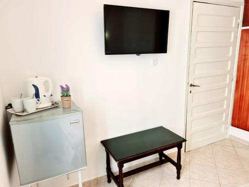 卡尔帕索斯Avra Rooms的客房设有冰箱、桌子和电视。