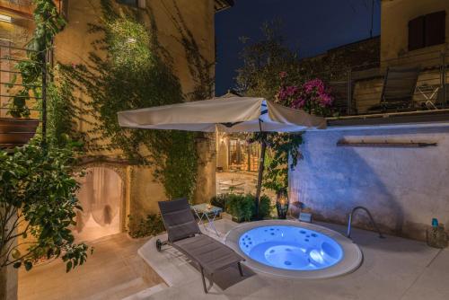 加尔尼亚诺Corte Alma Spa and Luxury Home的庭院内的热水浴池和遮阳伞