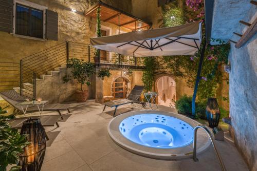 加尔尼亚诺Corte Alma Spa and Luxury Home的庭院内的热水浴池,配有遮阳伞