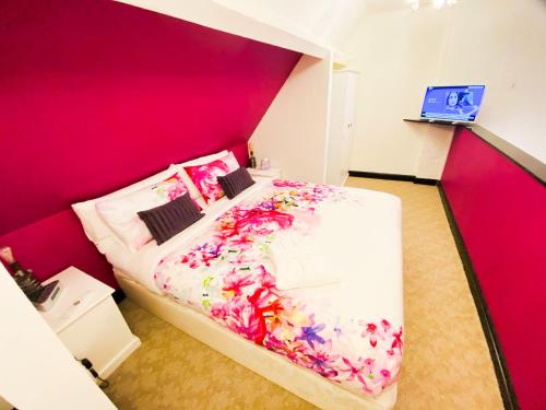古耳PHOENIX Apartments的卧室配有一张带粉红色墙壁的大床