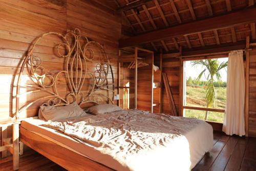 Phu YenTODO Farm - Organic Farming & Retreat的木制客房内的一间卧室配有一张大床