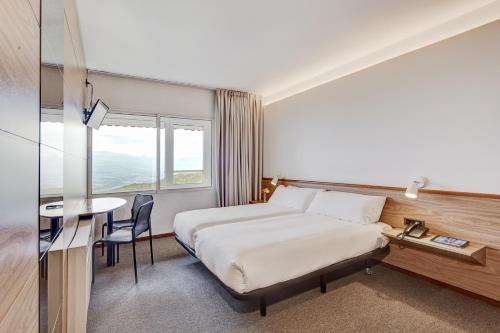 拉马塞拉Alp Hotel Masella的酒店客房配有一张床铺和一张桌子。
