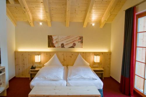 圣安东阿尔贝格瓦尔德贺酒店的一间设有两张床和两张桌子的房间