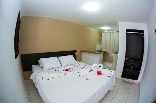嘎林海斯港Pousada Maravelas By OM的卧室配有一张白色大床,床上有红色的鲜花