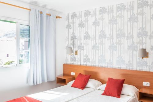 戈梅拉岛圣塞瓦斯蒂安Hotel Apartamentos Villa Gomera的一间卧室配有一张带两个红色枕头的床