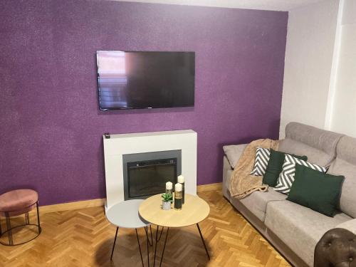 萨拉曼卡Dúplex CENTRICO LA RANITA SALMANTINA的客厅设有壁炉和紫色墙壁上的电视
