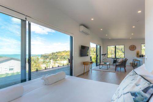 欧尼罗亚Luna Cottage. Stunning ocean views on Waiheke的卧室设有白色的床和大窗户