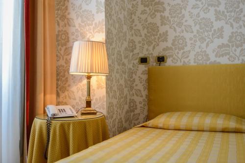 的里雅斯特阿尔伯格亚拉珀斯塔酒店的一间卧室配有一张带台灯的床和一部电话