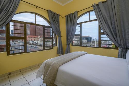 德班Ushaka Holiday Apartments的一间卧室设有一张床和两个大窗户