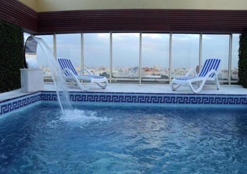 吉达Areen Hotel Airport的一个带两把椅子的游泳池和一个喷泉
