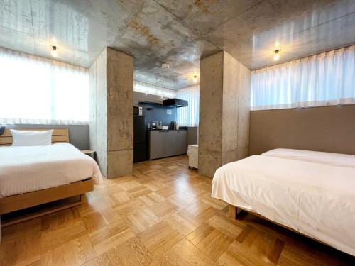 东京PRISM INN OGU的客房内设有两张床,铺有木地板,设有窗户。