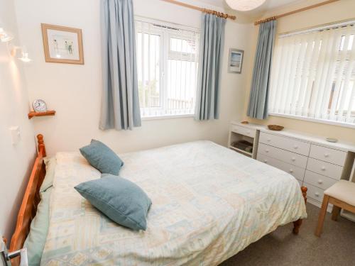 海景城Buddleia Cottage的一间卧室设有一张床和两个窗户。