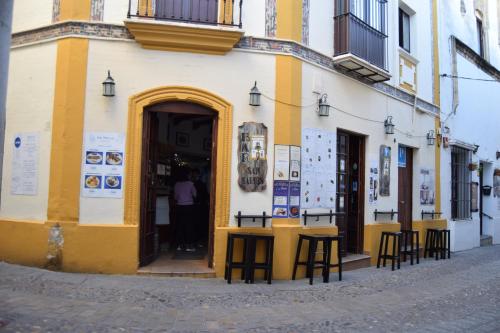 阿尔科斯-德拉弗龙特拉圣马科斯旅馆的一座黄色和白色的建筑,外面配有桌椅