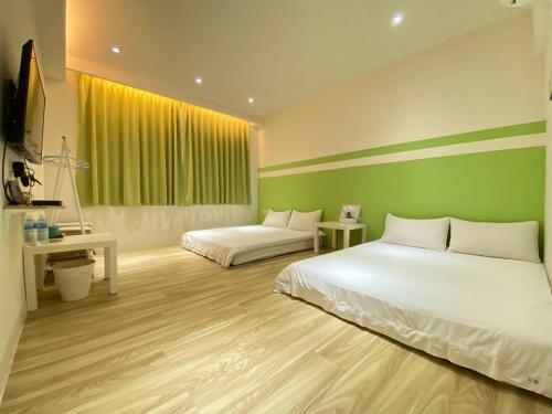 台南吉寓 的一间卧室设有两张床和绿色的墙壁