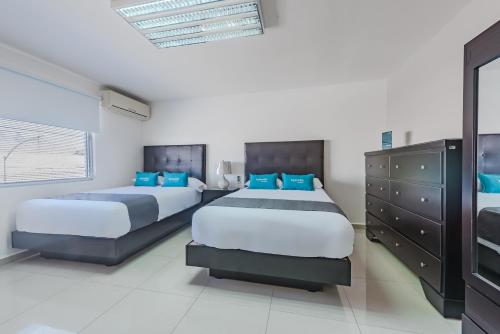 蒙特雷Ayenda Suites Ejecutivas Monterrey的卧室内的两张床,配有蓝色枕头