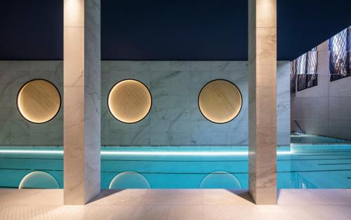 巴黎Hotel Lutetia的墙上有三个圆形灯的游泳池