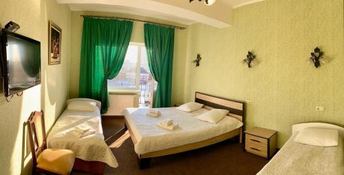 鲍里斯皮尔Golden Lion Hotel的客房设有两张床和一个带绿色窗帘的窗户。
