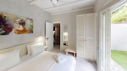 Agii SarantaYalos luxury home的卧室配有白色的床和墙上的绘画作品