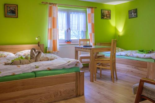 克拉利基Hotel Kačenka的一间卧室设有绿色的墙壁、两张床和一张桌子