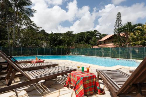 Matoury拉查米耶尔酒店的游泳池旁设有桌椅