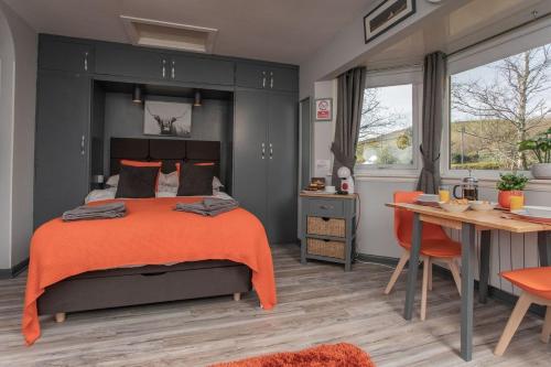 蒂恩格Soay@Knock View Apartments, Sleat, Isle of Skye的一间卧室配有一张带橙色毯子和桌子的床