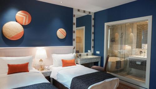 马六甲Sojourn Guest House Melaka的两张床铺,房间拥有蓝色的墙壁和橙色的枕头