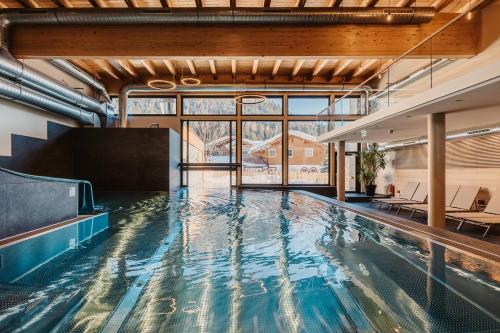 瓦格赖恩Hofgut Apartment & Lifestyle Resort Wagrain的一座带大窗户的建筑中的游泳池