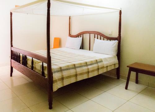 坎帕拉Etana Motel Kampala的一间卧室配有一张天蓬床和一张桌子