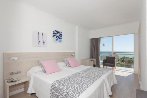 帕尔马海滩提摩尔酒店的一间卧室配有带粉红色枕头的床和窗户。