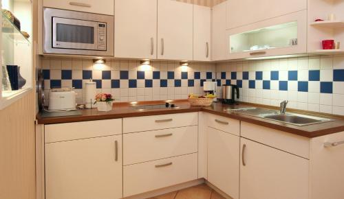 奥斯赛拜-屈隆斯博恩Ferienwohnung Antonia的厨房配有白色橱柜、水槽和微波炉