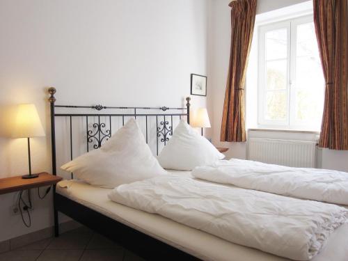奥斯赛拜-屈隆斯博恩Ferienwohnung Seeadler Nr. 7的一间卧室设有两张带白色床单的床和窗户。