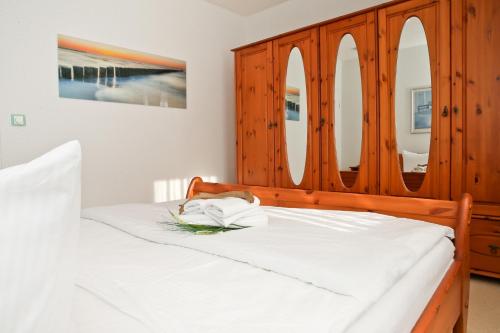 奥斯赛拜-屈隆斯博恩Ferienwohnung Katharina - Urlaub mit Strandkorb的卧室配有白色床和木柜